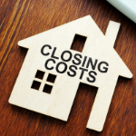 Beige cardboard cut out of a home with the words "Closing Costs" from a local mortgage lender.