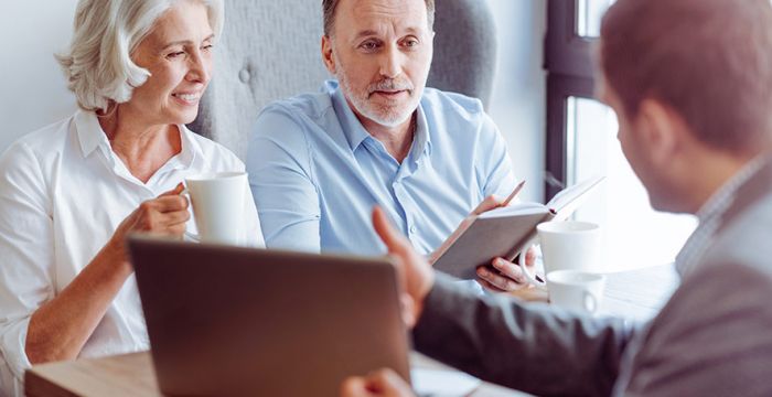 Mature couple consulting at desk with Lakewood Mortgage Lender for a refiannce.