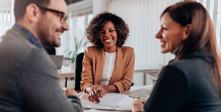 Man and woman smiling at each other in the foreground after deciding to go with the best local mortgage lender in the background.