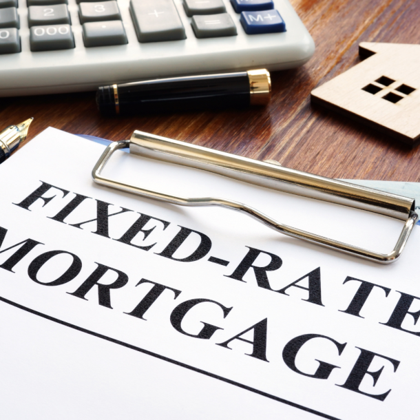 Clipboard holding papers from the best local lenders that read, "Fixed-rate Mortgage" with a calculator above and a cardboard cut out of a home to the right.